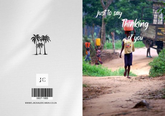 Child walking along a dirt path with palm trees in the background.