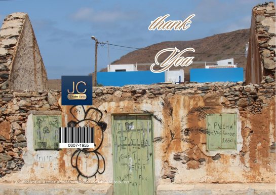 Weathered building with green doors, a blue sign, and a decorative 'thank you' text above.