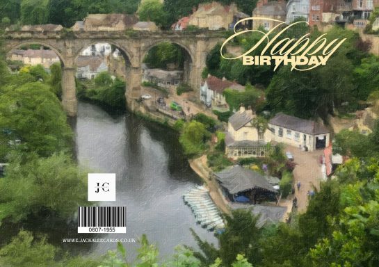 A scenic view of a river, bridge, and quaint village with a birthday greeting overlay.