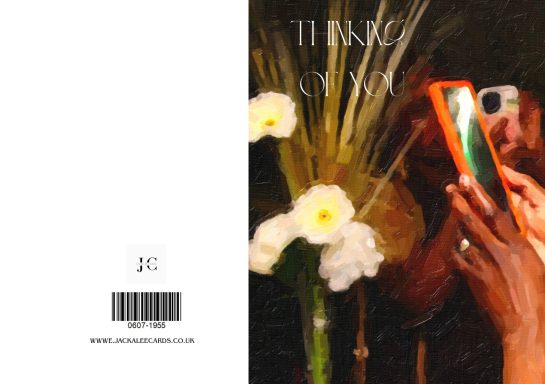 A hand holding a phone captures a floral arrangement with a dark background.